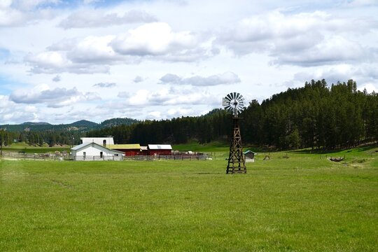 a grassy field with a farm and windmill in the distance