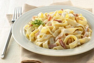 Italian tagliatelles with carbonara sauce on white plate