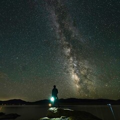 a man standing on the edge of a mountain with a bright flashlight