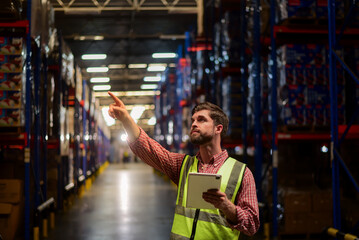Smart caucasian man warehouse worker wearing safety vests checking inventory stock online information with tablet in Logistic or distribution center.Inspecting products before delivering to customers.