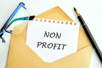 Non profit text an inscription on a piece of paper peeking out of an envelope next to glasses and a...