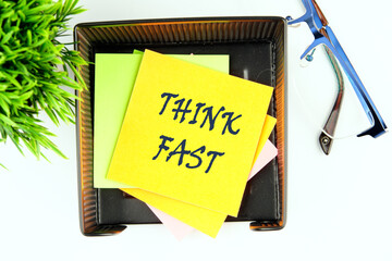 THINK FAST words on a yellow sticker in a stand on a white background, top view