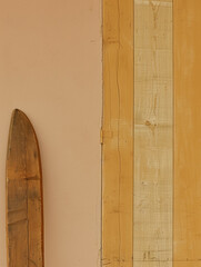 A wooden ski pole is leaning against a wall. The wall is painted a light color