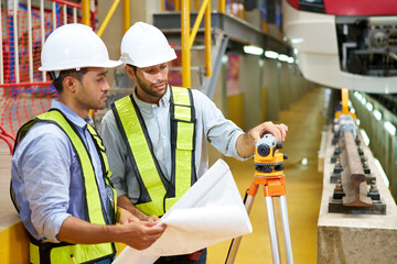 workers or engineers working and checking surveyor telescope at construction train station