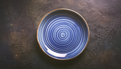Empty round blue plate on dark textured stone background. Ceramic tableware. Top view