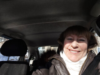 Middle aged woman in a car taking selfie while enjoying a drive. Female mature driver posing inside car. Funny happy tourist girl in alone travel