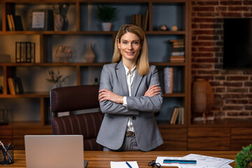 Young confident smiling  business woman leader, successful entrepreneur, elegant professional company executive ceo manager, wearing suit standing in office with arms crossed