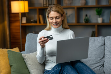 Woman is holding credit card and using laptop computer. Online shopping concept. Picture showing pretty woman shopping online with credit card