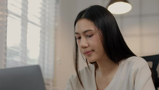 A beautiful Asian female entrepreneur is eating an instant noodles while working, she is consuming instant food in a hurry because of the deadline is coming, hungry but had to finish work in time