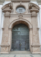Fototapeta na wymiar Entrance iron doorway and Decorated arch wall of St. Michael's Church (Michaelskirche Jesuit church) in Munich pedestrian zone. It is the largest Renaissance church north of the Alps. Space for text, 