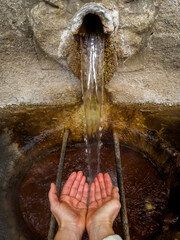 Catching Water from an Ancient Stone Fountain