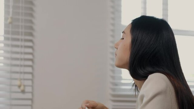 A beautiful Asian female entrepreneur is eating an instant noodles while working, she is consuming instant food in a hurry because of the deadline is coming, hungry but had to finish work in time