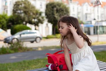 Cute little girl sitting on a bench and listening to music with headphones