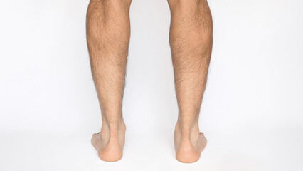 Adult male feet seen from behind observing Achilles heels and calves, with a white background