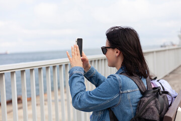 Side view of a woman taking a selfie on the promenade