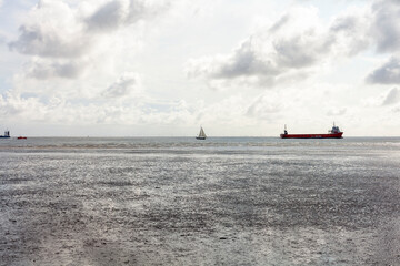 Seascape with cargo ship in the sea and cloudy sky.