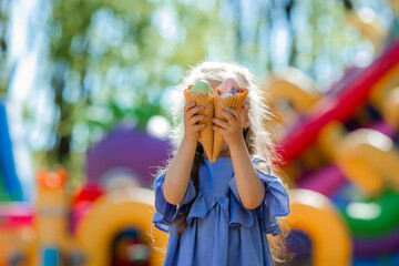 happy little girl eats ice cream in the park in the summer