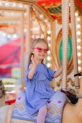 A happy little girl rides a carousel in the summer at an amusement park © Tina kids photo