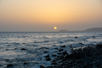 Beautiful orange sunset over the sea with stones on the beach