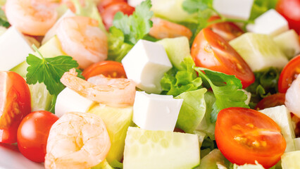 A close-up salad of fresh vegetables, a plate of fresh salad with vegetables and herbs. Greek salad with juicy tomatoes, feta cheese lettuce leaves green olives cucumber, fresh parsley. Homemade food.
