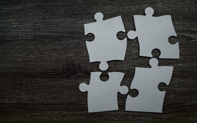 4 Four white carton paper pieces of puzzle lie on wooden table isolated on gray background. empty copy space for inscription or objects. idea, sign, symbol, concept of connecting.