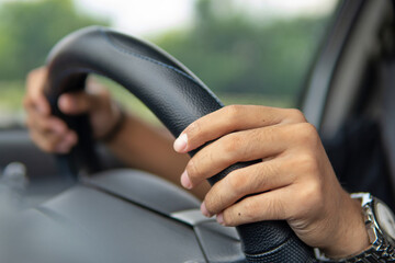 Closeup image of male driver hands holding steering wheel.