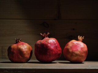 Red organic grown pomegranates in bright sunlight with copyspace. Natural fruit concept image.