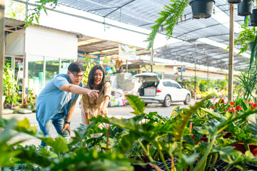 Happy Asian family adult couple choosing and buying plant together at plant shop street market on...