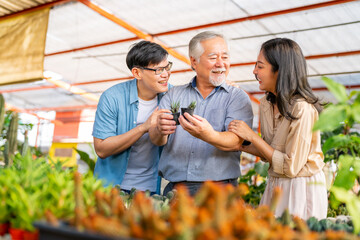 Adult Asian couple with elderly man father choosing and buying plant at plant shop street market on...