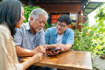 Happy Asian family adult couple teaching elderly father using mobile phone application in the...