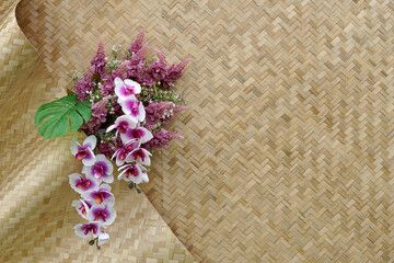 Bamboo woven mats are decorated with beautiful colorful plastic flowers. Used to decorate the backdrop to take pictures of various events. who want a natural look. soft and selective focus.