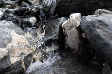 sparkling mountain stream close up view . natural fresh water is coming out of the massive mountain