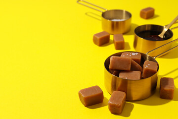 Cubes of salted caramel with salt on a yellow background