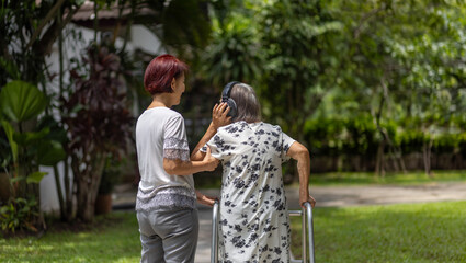Elderly woman exercise walking in backyard with daughter.