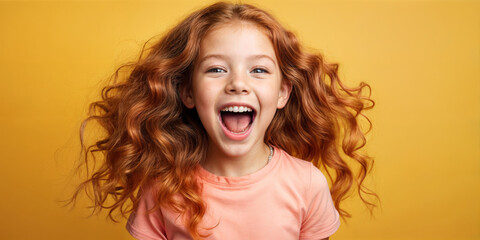 Cute young child  Little girl smiles. Emotion and child development. Little girl smiles while red hair.  A young girl with curly hair is smiling and laughing while wearing a shirt.