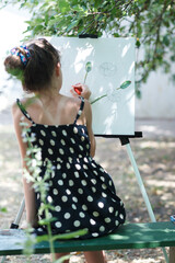 A girl is painting a picture on an easel.