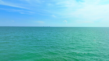 A drone's eye reveals a tranquil sea meeting a boundless blue sky, merging seamlessly in nature's...