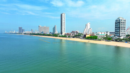Obraz premium A breathtaking beachscape: Azure waters meet towering coastal skyscrapers in a mesmerizing drone view. Famous sites captivate tourists universally. Jomtien Beach, Pattaya, Thailand. Tourism industry. 