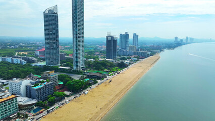 Fototapeta premium Crystal-clear turquoise waters caress the golden sands, while elegant coastal buildings stand tall, creating a picturesque backdrop. Iconic landmarks draw tourists globally. Jomtien Beach, Thailand. 