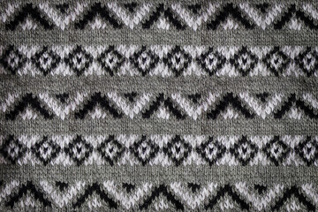 Close-up jacquard texture knitted on needles. Knitted background with black and white pattern