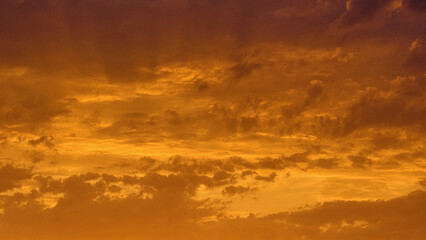 Sunset sky with stormy dark cloud. Golden yellow sunlight in the evening. Summer tropical holiday...