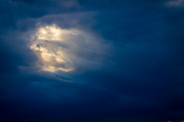 Evocative image capturing sunlight piercing through a dramatic cloud cover, depicting a sense of...