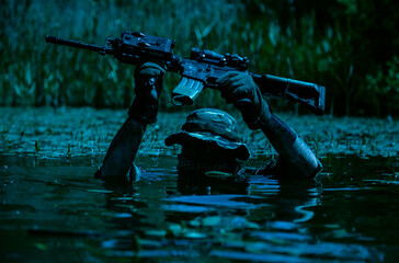 Obraz premium A soldier moves in the heart of a marsh, submerged in swampy waters with only arms and rifle visible, extreme conditions of concealed tactical combat night operation