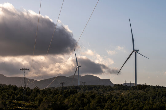 Silhouetted power lines and windmills against the backdrop of a sunset sky signify park eolic and the quest for green energy and environmental harmony