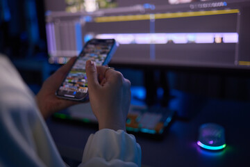 a woman is using a cell phone in front of a computer screen