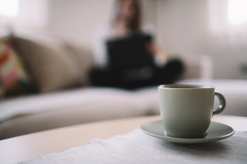 Selective focus of cup of coffee with  woman  silhouette in the background.