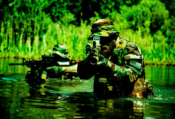 Soldiers move in the heart of a marsh, crossing swampy waters, tropical jungle heat, extreme...