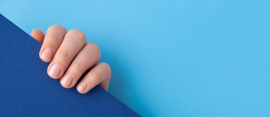 Pastel softness manicured nails on blue background. Mock up template copy space Woman showing her new manicure in colors of pastel palette. Simplicity decor fresh spring vibes earth-colored neutral