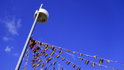 Small and festive rainbow flags tied to street light pole to celebrate Gay and LGBT Pride Month