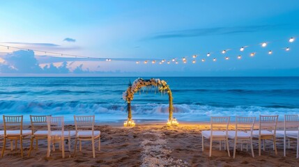 Empty beach event setup with white floral arch and string lights, serene ocean backdrop, early morning light enhances the calm mood